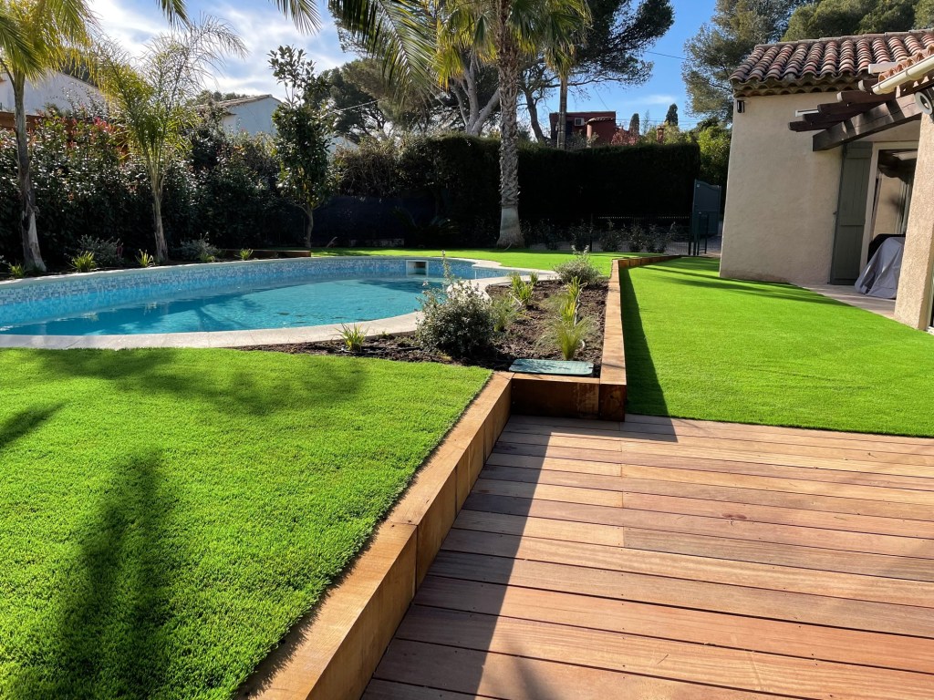 Création de jardin complet autour d'une piscine avec massifs pelouse artificielle et terrasse en bois prolongement maison. Saint-Raphaël 83700