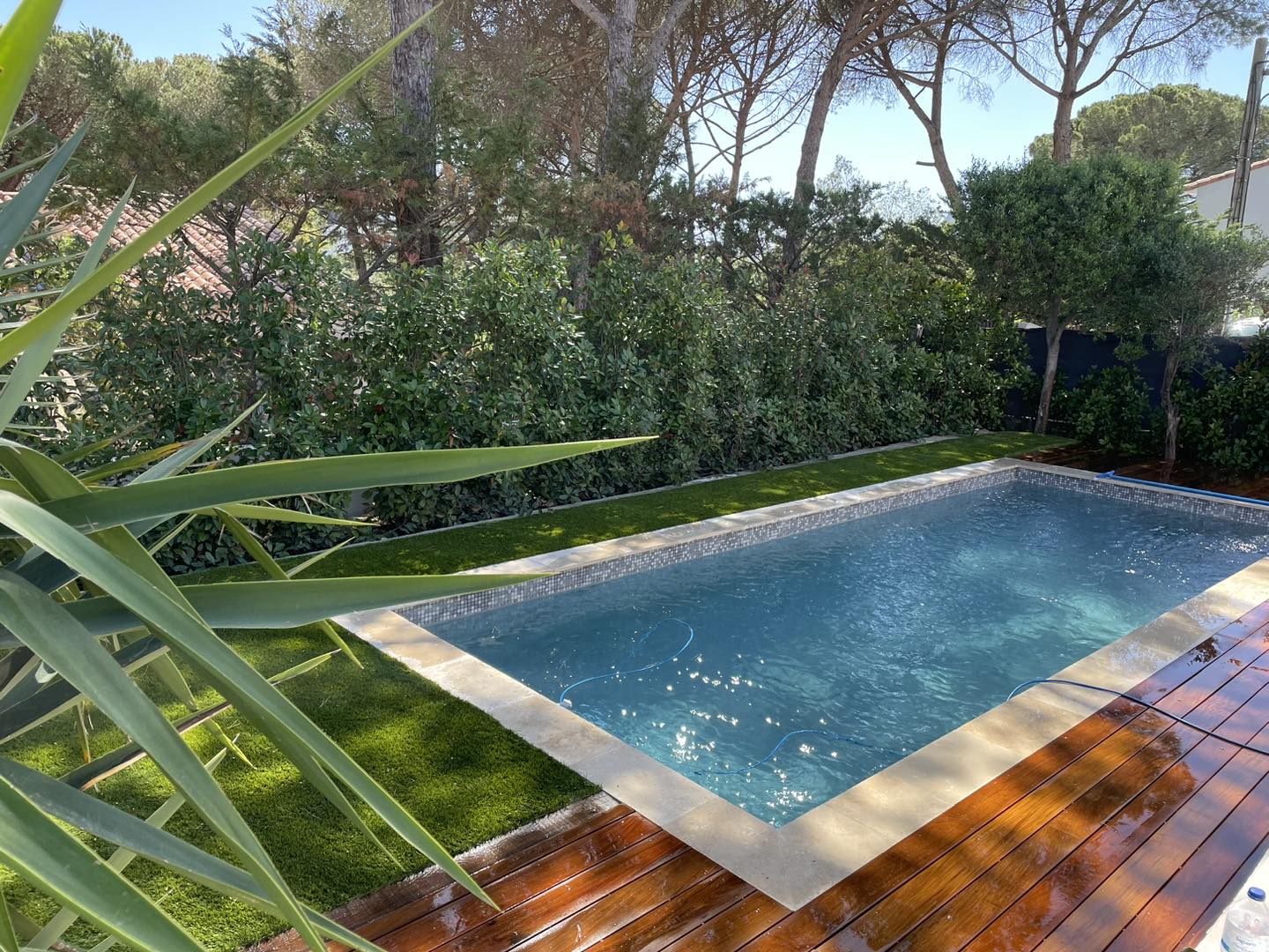 Terrasse en bois pourtour d'une piscine à Puget-sur-Argens. Gazon synthétique petite superficie. Aménagement petit jardin.