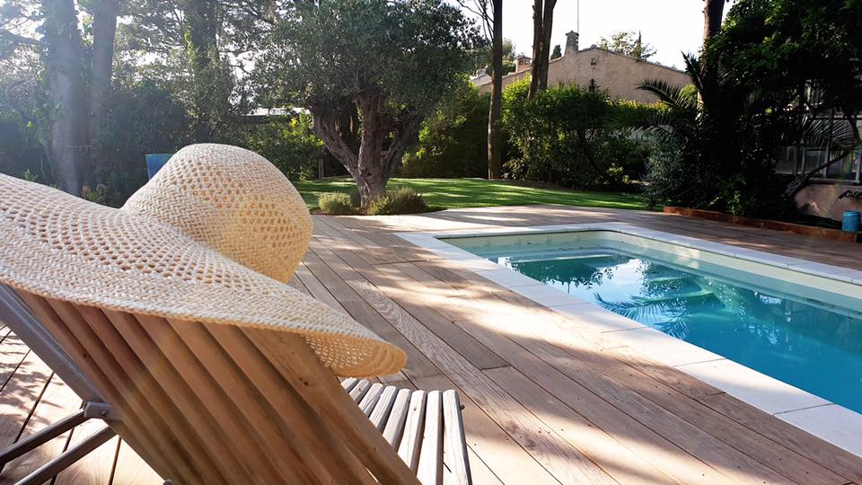 Terrasse en bois exotique autour d'une piscine enterrée. Fréjus centre. Gazon synthétique grande surface avec massifs et arbres.